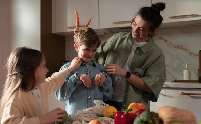 Mother and children have fun unpacking vegetables in the kitchen.