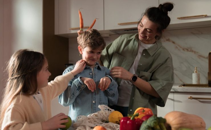 Mother and children have fun unpacking vegetables in the kitchen.